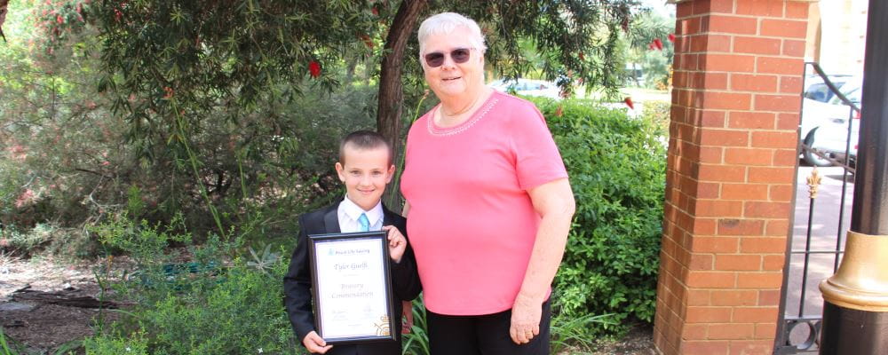 Tyler Guelfi with family friend Dale Bolin holding his Royal Life Saving Bravery Award outside Government House
