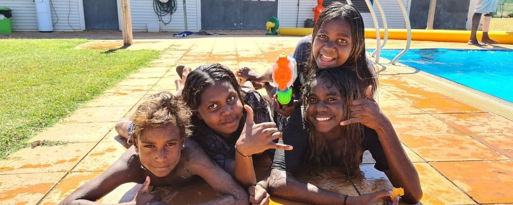 Four Aboriginal children laying by the pool at Warmun