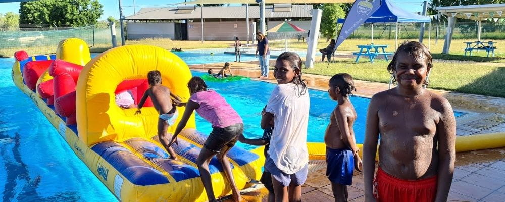 A group of Aboriginal children lining up to go on the inflatable in Warmun Pool