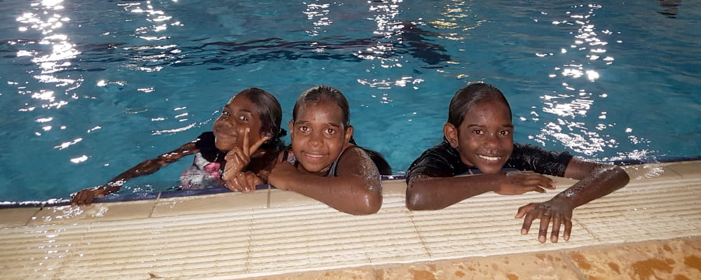 Three Aboriginal girls in the pool at night in Warmun