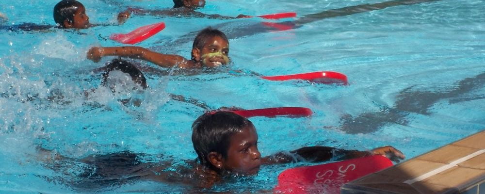 Aboriginal boys swimming with red Swim and Survive kickboards