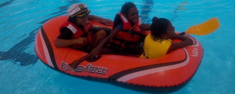 Three aboriginal children in a boat in the pool