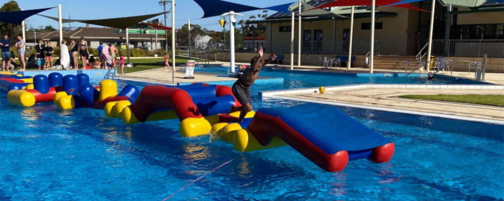 An Aboriginal boy on a large inflatable in a swimming pool