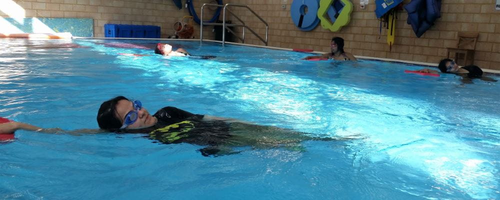 a woman swimming in a pool with a kickboard