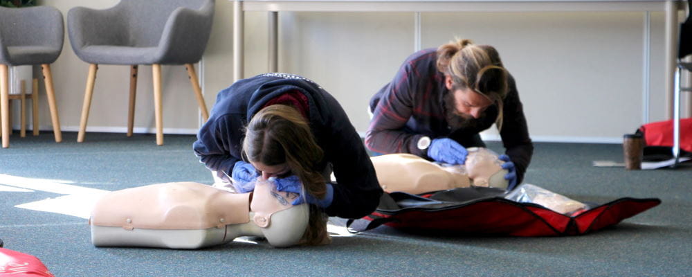 Two people practising CPR in a first aid course