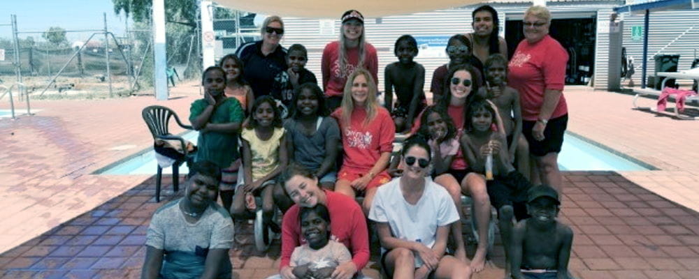 A group of swim instructors with Aboriginal children by the pool at Yandeyarra