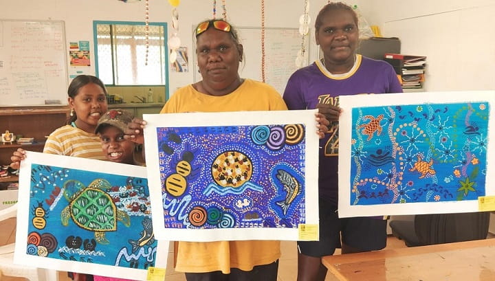 three Bidyadanga artists holding their work
