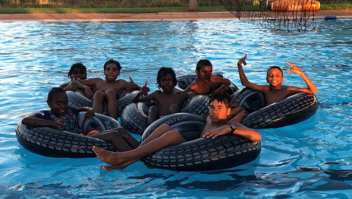 Aboriginal children sitting on inflatable tubes in the pool