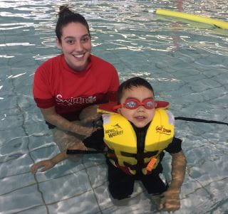 a swim instructor with a child wearing a lifejacket in the water