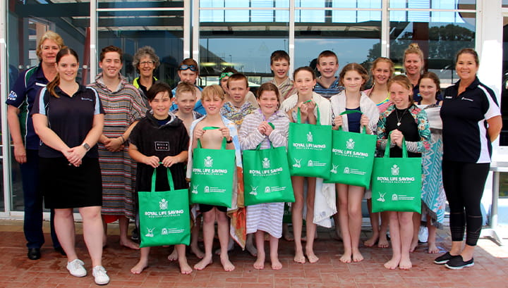 Students and coaches at the Bay of Isle leisure centre holding junior lifeguard club bags after swimming event