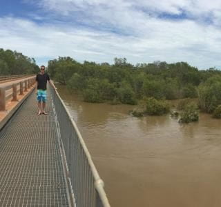 RLSSWA's Greg Tate standing on a bridge by a very swollen Fitzroy River