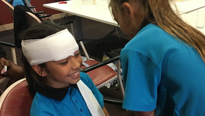 students practise bandaging each other's heads
