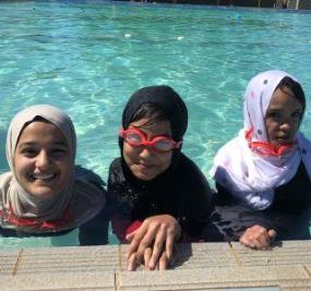 Three girls in Muslim headdress at the edge of the pool at Lynwood