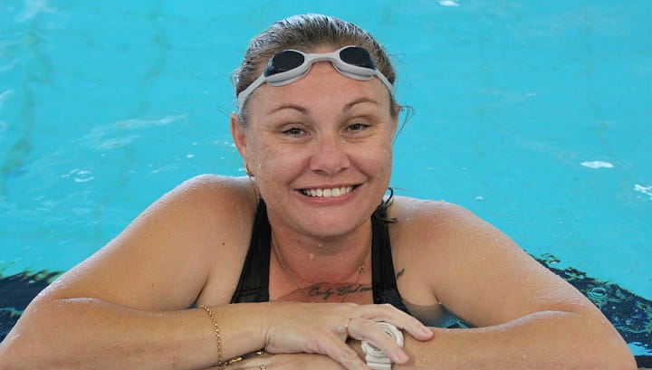 Swim Instructor Marianne Mallard smiling from the edge of swimming pool