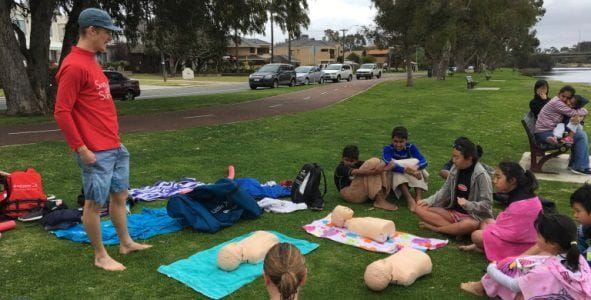 children preparing to learn CPR skill.s on the banks of the Swan River