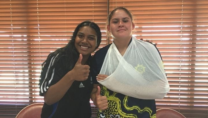 Two Aboriginal girls giving a thumbs up, one with a bandaged arm