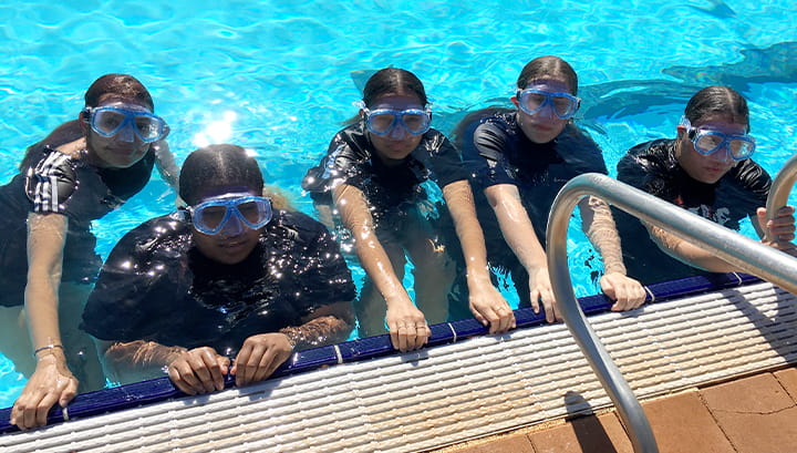 Five girls from Hedland SHS in a pool wearing goggles