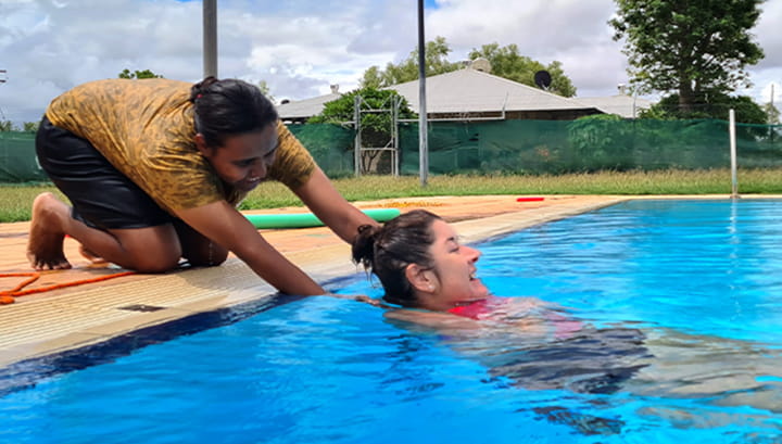 woman pulls another woman from pool as part of bronze medallion course