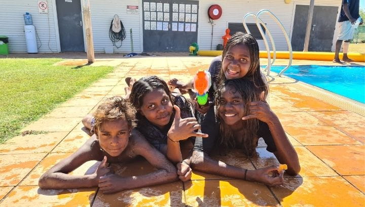 Four Aboriginal children laying by the pool at Warmun