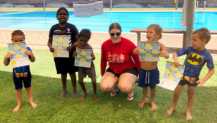 5 Indigenous children holding swimming certificates with their swimming teacher