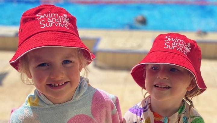 two girls wearing hats and poncho towels at a pool