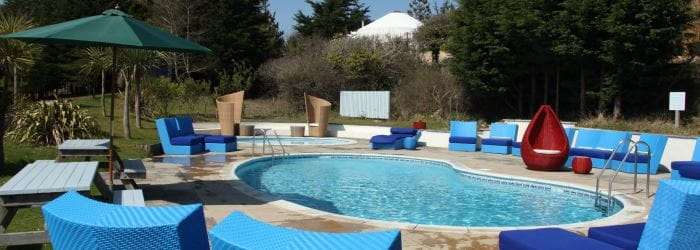 image of motel pool with blue chairs around the perimetre and a green umbrella