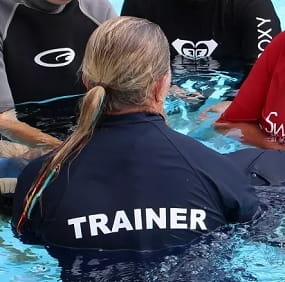 close up of aquatic trainer in pool with group of students