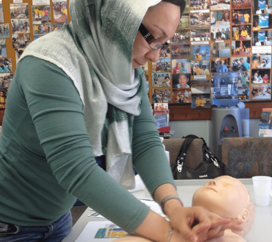 woman practising infant CPR on a baby manikin