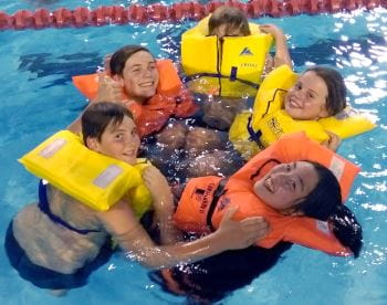 Children wearing lifejackets while in the pool smiling