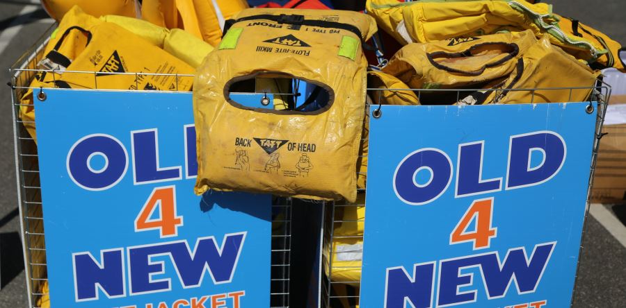 Old yellow foam lifejackets in a basket with an Old 4 New Lifejacket sign
