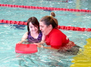 Sahara with her instructor in the water with a kickboard