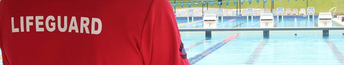 close up of the back of a lifeguard supervising an outdoor swimming pool