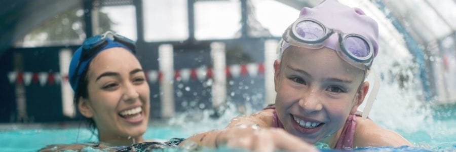 Instructor in water with student teaching swim strokes