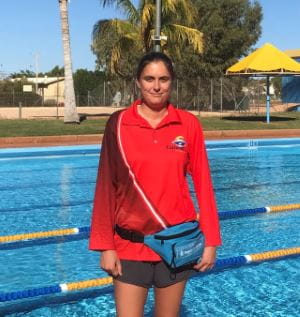 Erin French wearing a red jumper and blue bumbag, standing by the pool at Exmouth