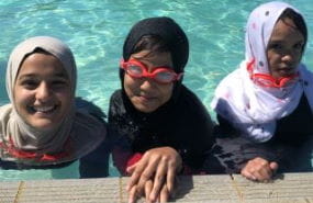 Three Muslim girls in the pool wearing traditional clothing