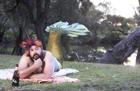 A man dressed as a mermaid by the river