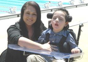 Simone crouching by her son Ari who is in a wheelchair