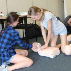 Image of two young girls practising CPR on a manikin