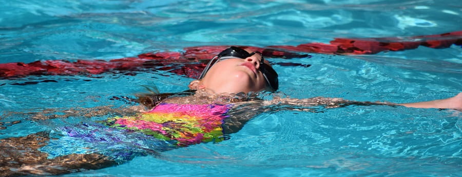 close up of young girl doing backstroke in a public pool