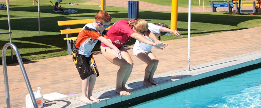 swim teacher showing students how to dive correctly