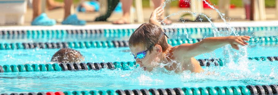 A young boy swimming butterfly, wearing goggles