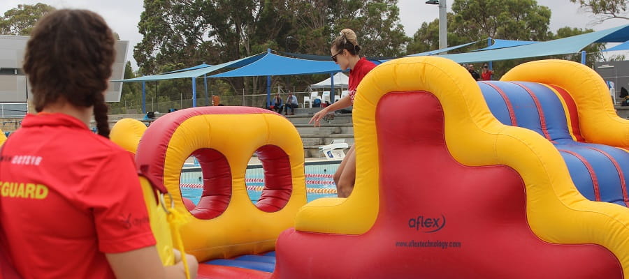 lifeguard supervising giant inflatable at public swimming pool