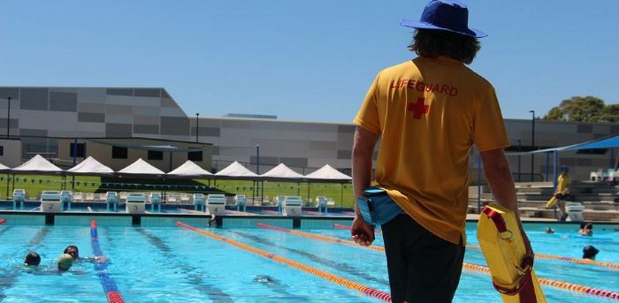 a lifeguard by the pool carrying a rescue tube