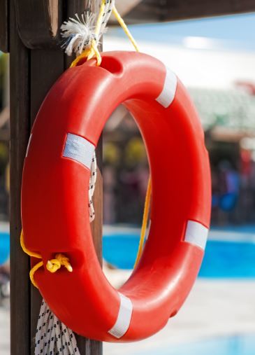 traditional lifesaving ring hanging on a post near a swimming pool