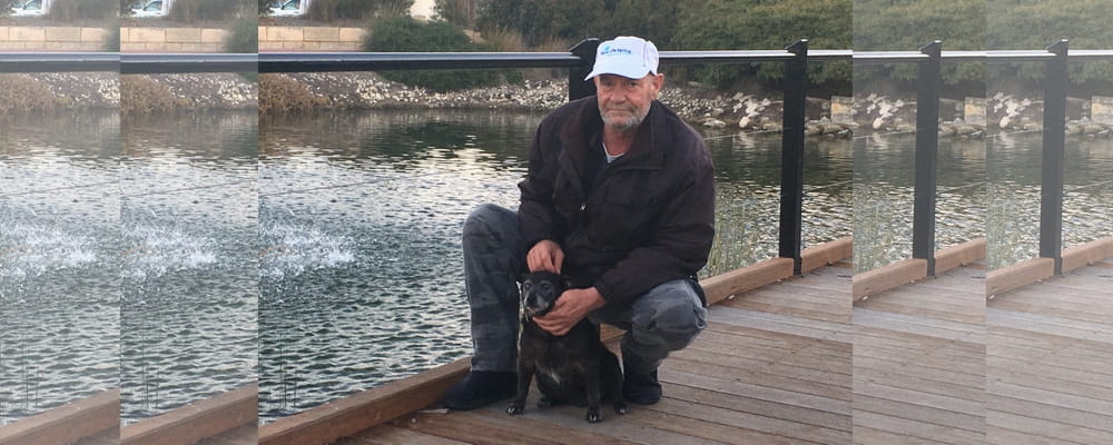 MIchael Faassen and his dog Rocket sit on a footbridge where Rocket recently was rescued.