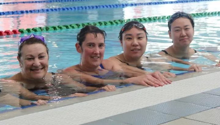 women in swimming pool smiling at camera