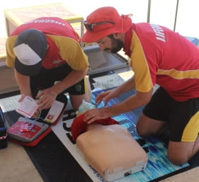 image of two lifeguards performing defibrillation on a CPR manikin