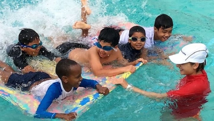 swimming instructor with five students on float mat