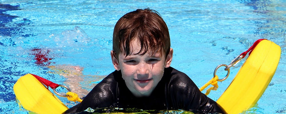 young boy in pool propped up by rescue tube