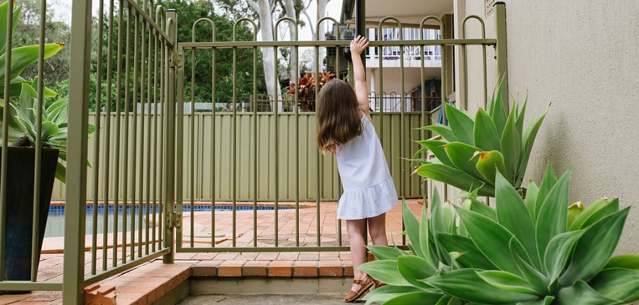 young girl standing outside pool fence